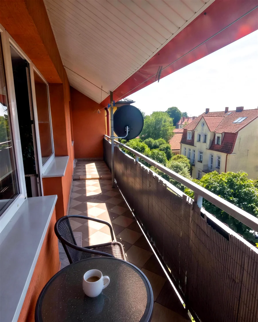 Duży balkon z widokiem na zieleń, stolikiem i kawą