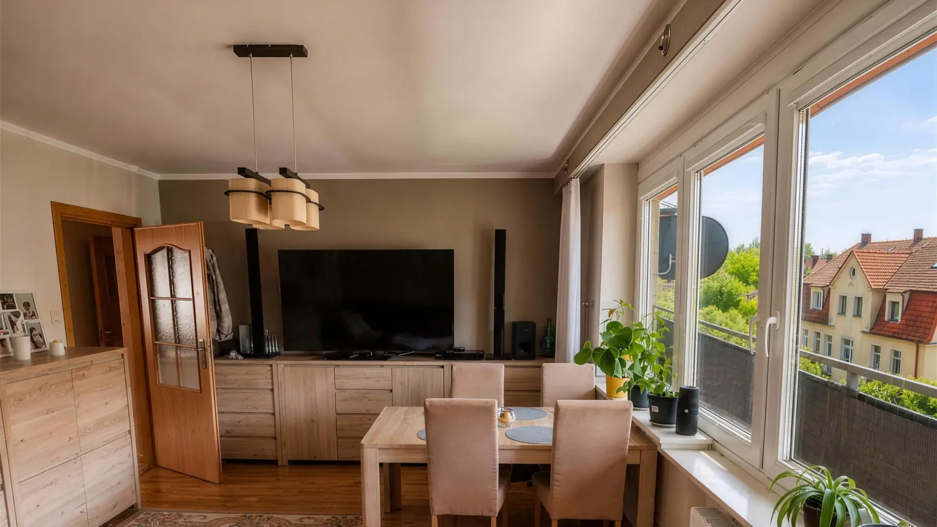 Salon z dużymi oknami, jadalnią i wyjściem na balkon